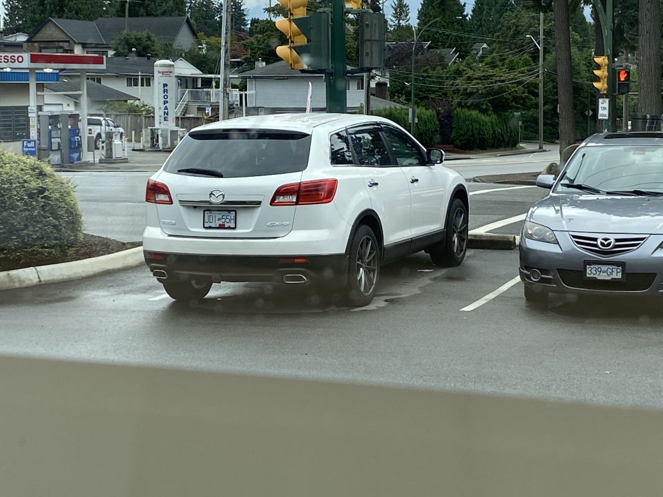 White 2009 Mazda CX-9 rear 3/4 view parked next to a grey Mazda sedan.