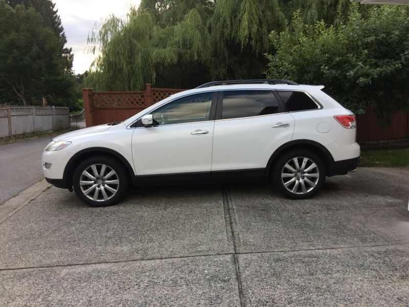 White 2009 Mazda CX-9 parked on a concrete driveway, side view.