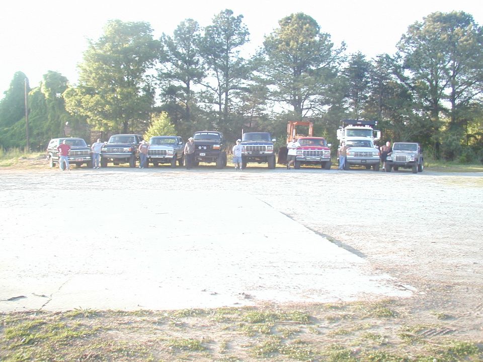 Several trucks and SUVs parked in a lot, including a red pickup truck and a gray Jeep