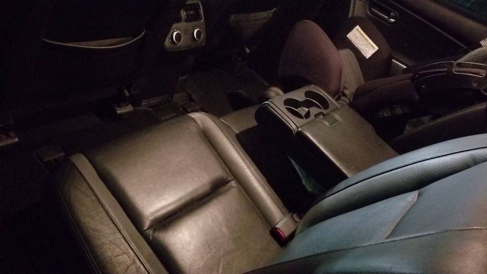Interior of a dark SUV showing leather seats, center console, and rear air vents.