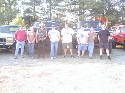 1988 Ford Bronco - Several people pose with their lifted trucks, with one truck displaying a banner that reads 'SIZE DOES MATTER!'
