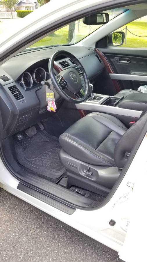 Interior of a white Mazda CX-9, driver's seat, dashboard, steering wheel, air freshener.