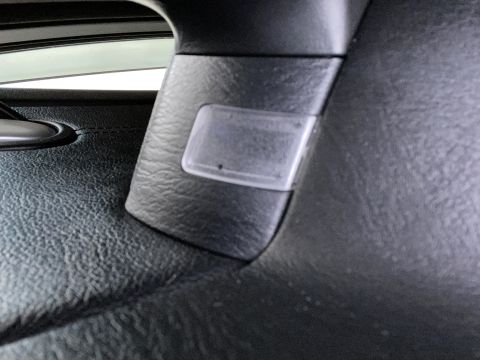 2009 Mazda CX-9 - A close-up interior shot shows a clear plastic cover over a small light or sensor on the black textured pillar of a vehicle.
