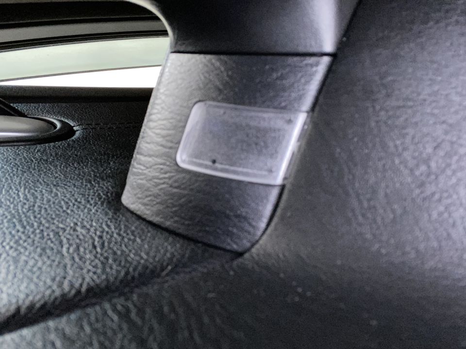 Close-up of a clear plastic cover on a black textured pillar inside a vehicle.
