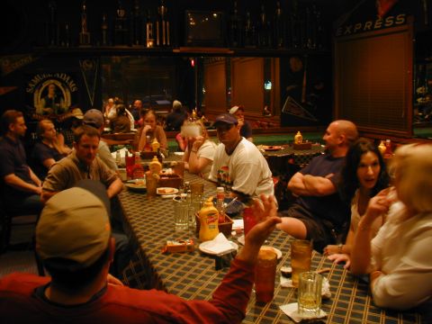 1988 Ford Bronco - A group of people are seated at tables in a restaurant, with trophies displayed on shelves in the background.
