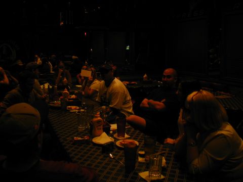 1988 Ford Bronco - A group of people are gathered around tables in a dark room, possibly at an event or gathering.
