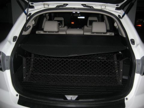 2009 Mazda CX-9 - The open rear cargo area of a white SUV is shown, featuring a black cargo net stretched across the space behind the rear seats. A retractab…