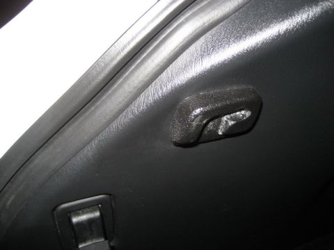 2009 Mazda CX-9 - A close-up interior shot shows a black plastic hook attached to the dark gray interior trim of a vehicle. A black latch is also visible in…