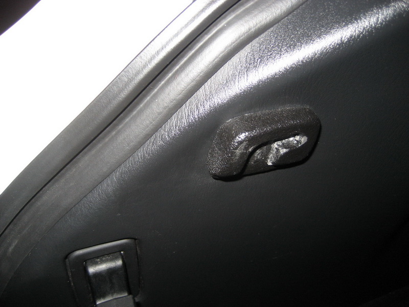 Close-up of a black plastic hook and latch on a car's interior trim.