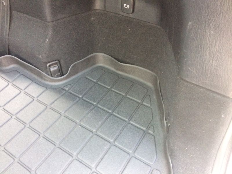 Close-up of a black, grid-patterned cargo mat in a vehicle's rear.