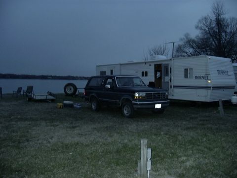 1992 Ford Bronco - A 1992 Ford Bronco is parked beside a travel trailer with a lake in the background.