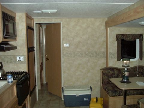 1992 Ford Bronco - The interior of a recreational vehicle features a compact kitchen area, a dinette, and a cooler.