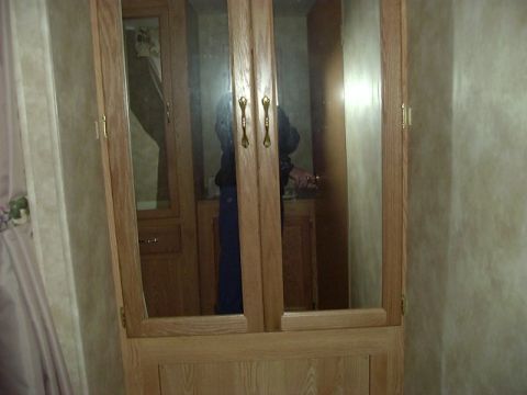 1992 Ford Bronco - Interior view of a wooden cabinet with mirrored doors, showing a reflection of a person.