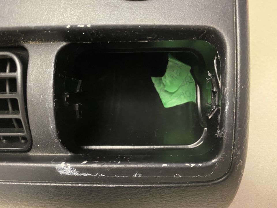 Interior car dashboard compartment with green tape and scratches.
