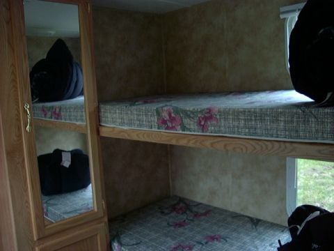 1992 Ford Bronco - Bunk beds with floral mattresses are visible inside a camper, with a mirrored closet door on the left.