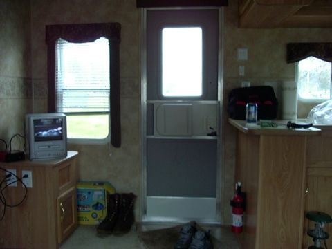 1992 Ford Bronco - The interior of a recreational vehicle shows a door, a window with blinds, and a small television set.