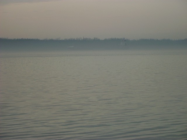 calm water with a distant treeline under a hazy sky. Supermotors logo in the corner