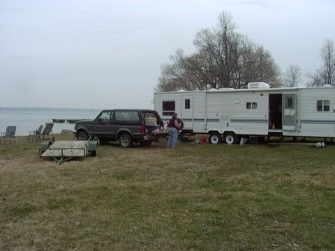 1992 Ford Bronco - A 1992 Ford Bronco is parked next to a travel trailer at a campsite near a body of water.
