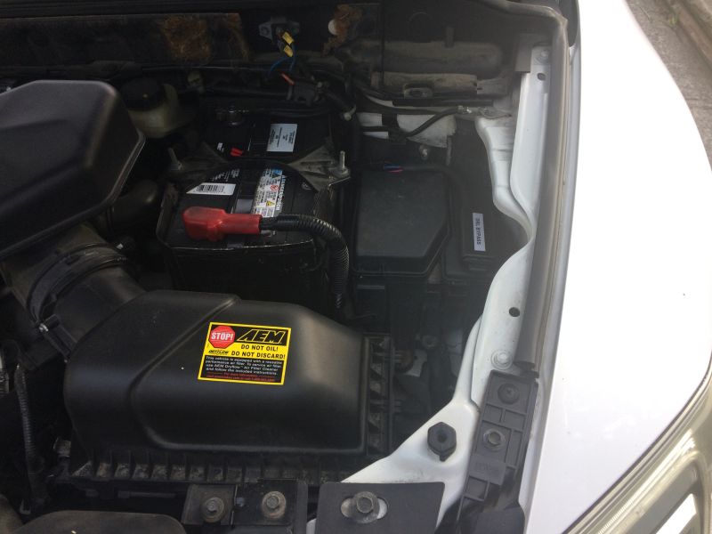 Engine bay of a Mazda CX-9 with battery, AEM air intake, and fuse box.