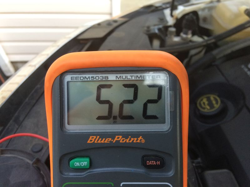 Blue-Point multimeter showing 5.22 volts, in a vehicle engine bay.