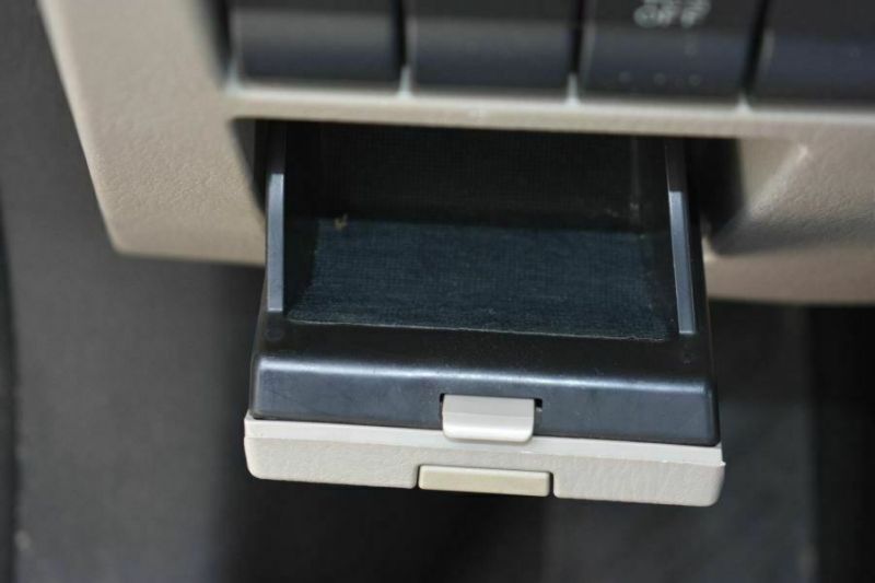 Open car storage compartment below dashboard buttons