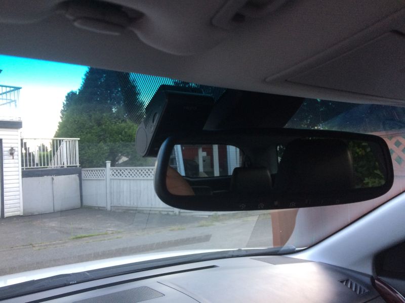Interior of a 2009 Mazda CX-9 with a dashcam mounted above the rearview mirror, showing a fence and trees outside.