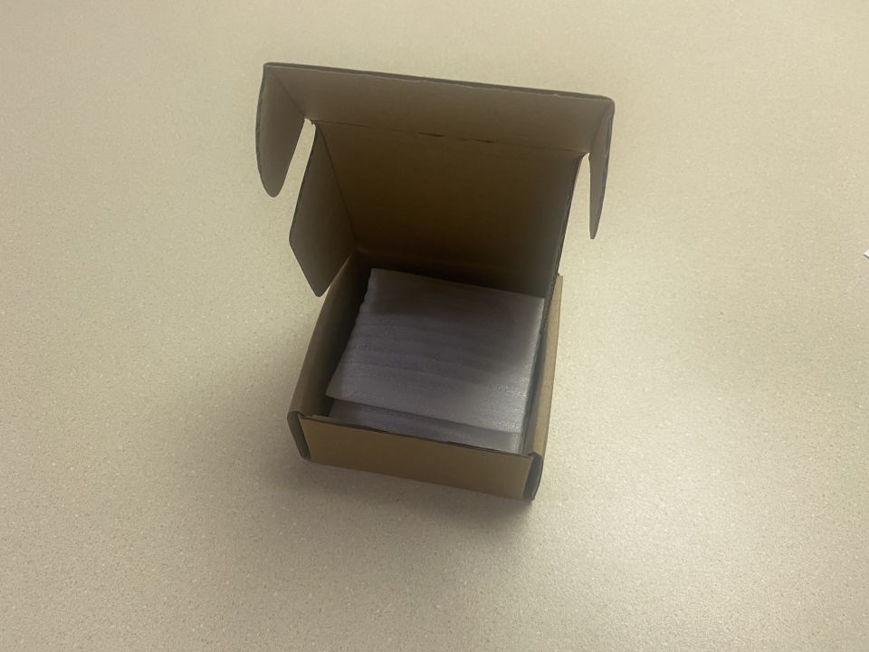 Open cardboard box with gray foam padding inside.