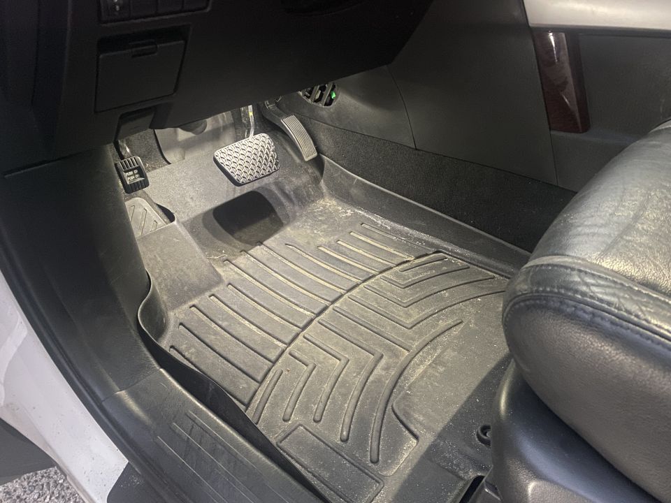 Driver's side interior of a vehicle showing floor mats and pedals.