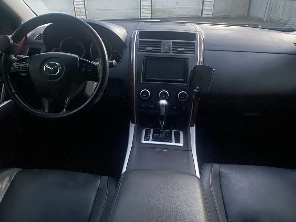 Interior view of a Mazda CX-9 dashboard, steering wheel, center console, and seats.