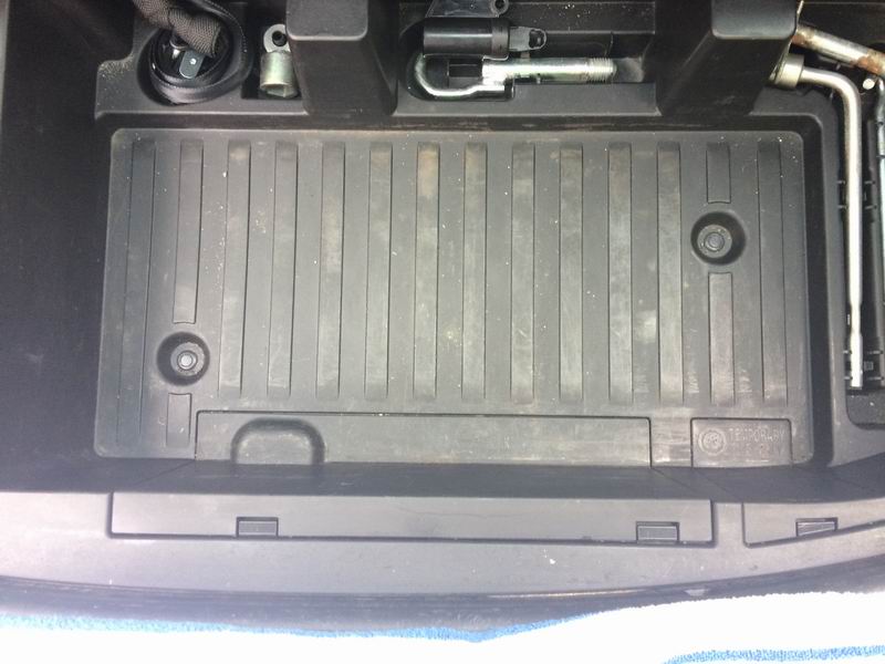 Spare tire well with tools and a ribbed plastic tray.