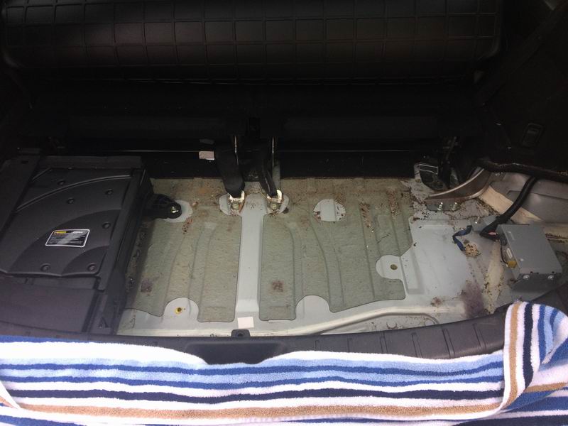 Interior of a vehicle cargo area with floor removed, showing undercarriage and components.