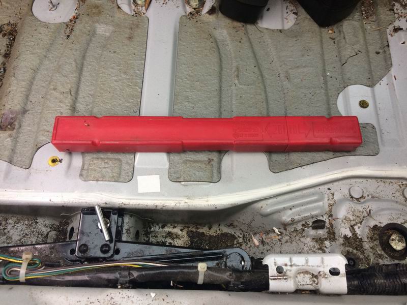 Red emergency triangle case and car jack in vehicle cargo area.