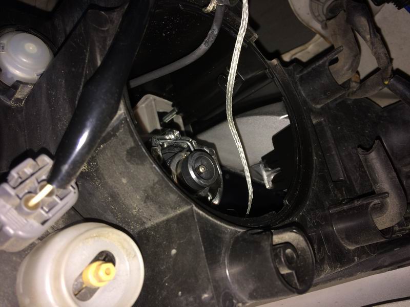 Left side: the low beam housing is right next to the fender. Twist off the weather cap, twist off the electrical connector, unclip the two bulb retainer arms (push in each arm so it can move outwards), pivot the retainer downwards and pull the bulb out.