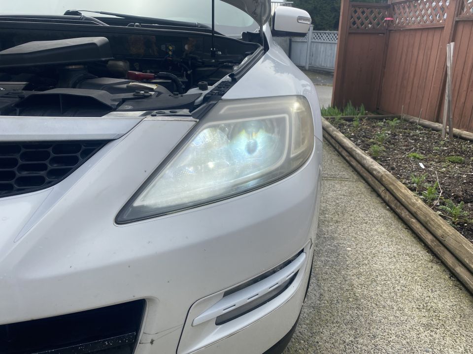 White 2009 Mazda CX-9 front passenger side, hood open, parked on driveway.