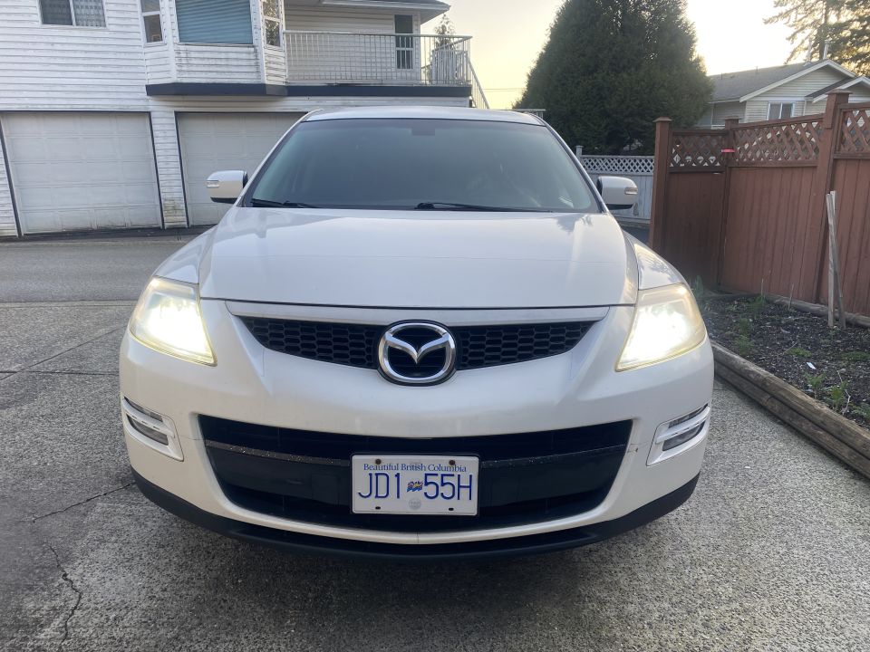 White 2009 Mazda CX-9 SUV front view with headlights on and BC license plate JD1 55H