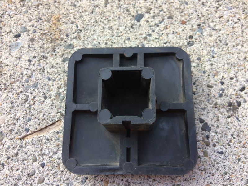 Black plastic square foot cap with hollow square opening on concrete