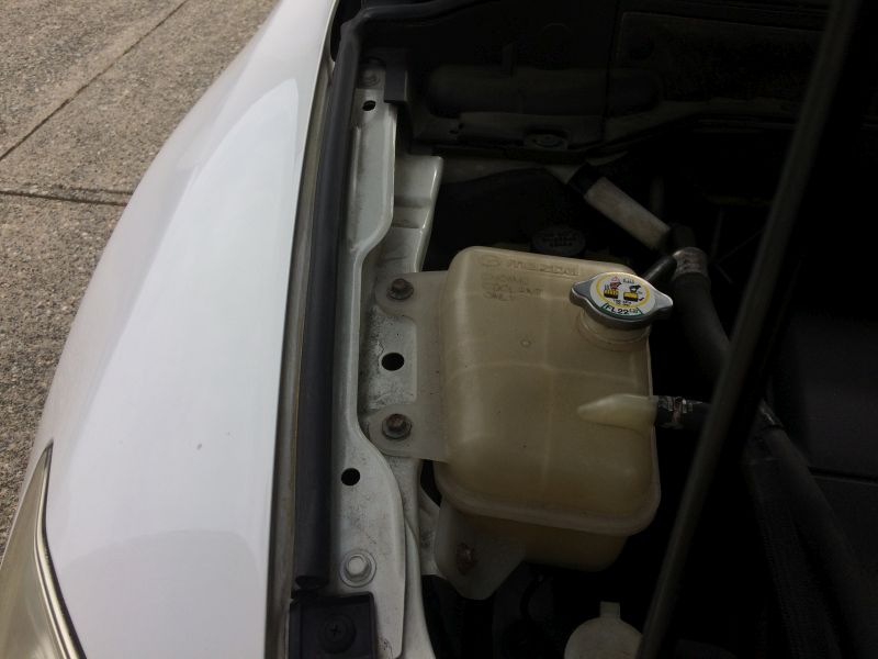 White Mazda CX-9 engine bay with coolant reservoir and cap