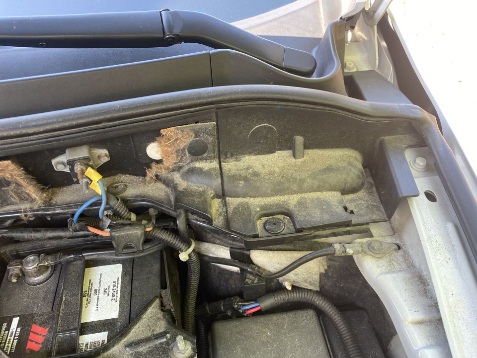 2009 Mazda CX-9 engine bay with battery and wiring, covered in dust.