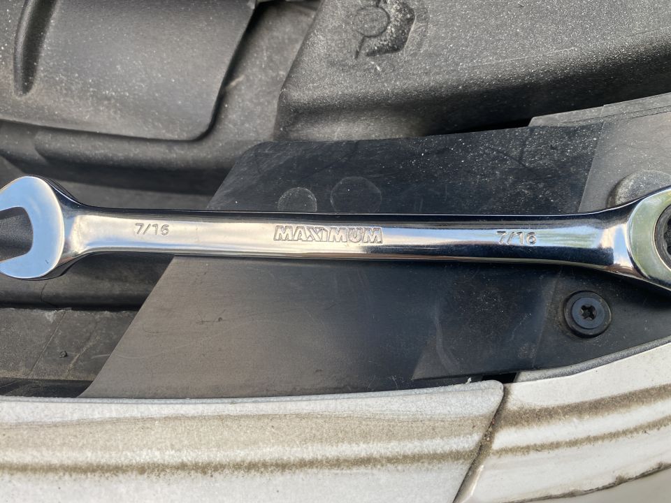 Chrome 7/16 inch ratcheting wrench on black plastic.