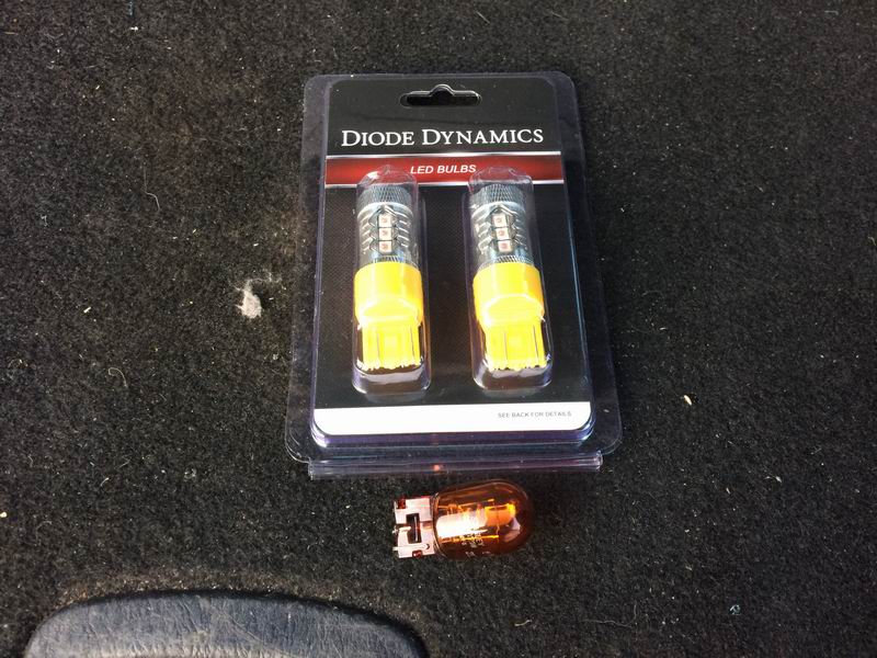 Diode Dynamics LED bulbs package next to an old amber bulb on carpet.