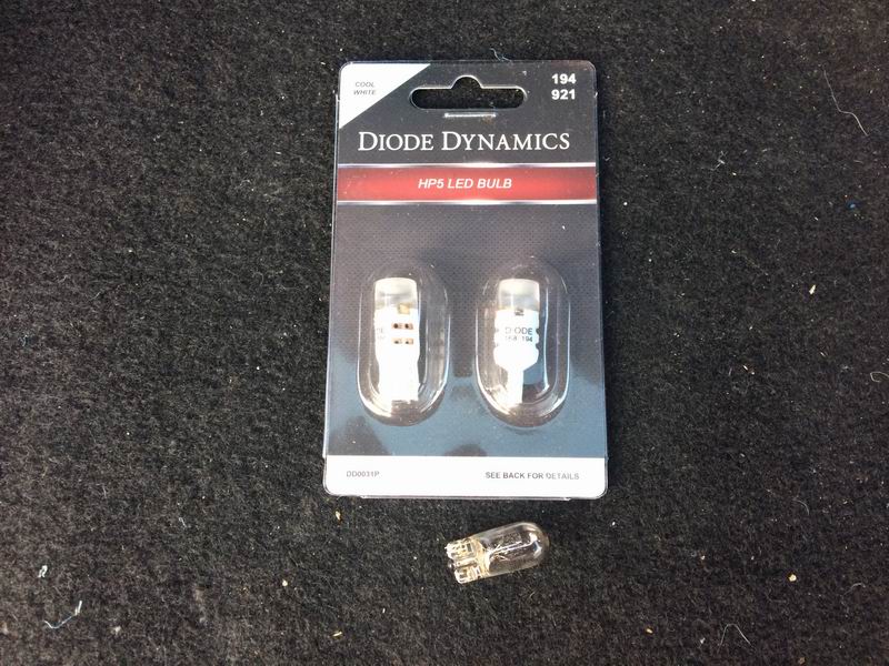 Diode Dynamics HP5 LED bulbs package with one bulb out of package on carpet.