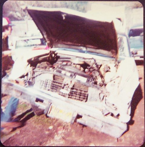 1974 Chevrolet Nova - The engine bay of a 1974 Chevrolet Nova is exposed with the hood up, revealing damaged components and the engine itself.