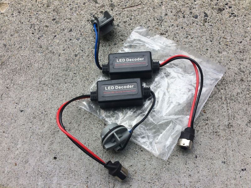 Two black LED decoders with wires and connectors on a concrete surface.