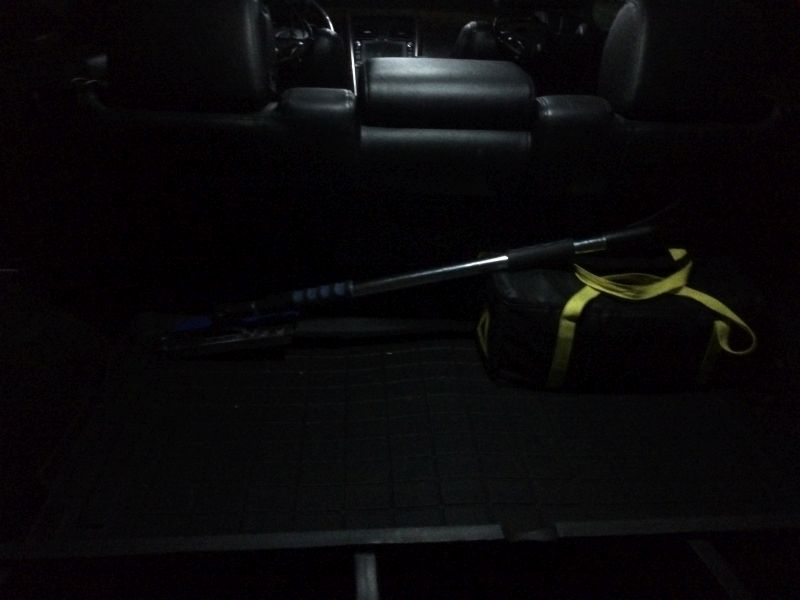 Interior cargo area of a vehicle with a duffel bag and collapsible shovel.