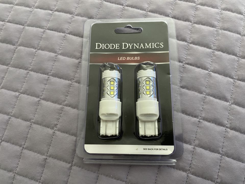Diode Dynamics LED bulbs in packaging on a quilted gray surface.