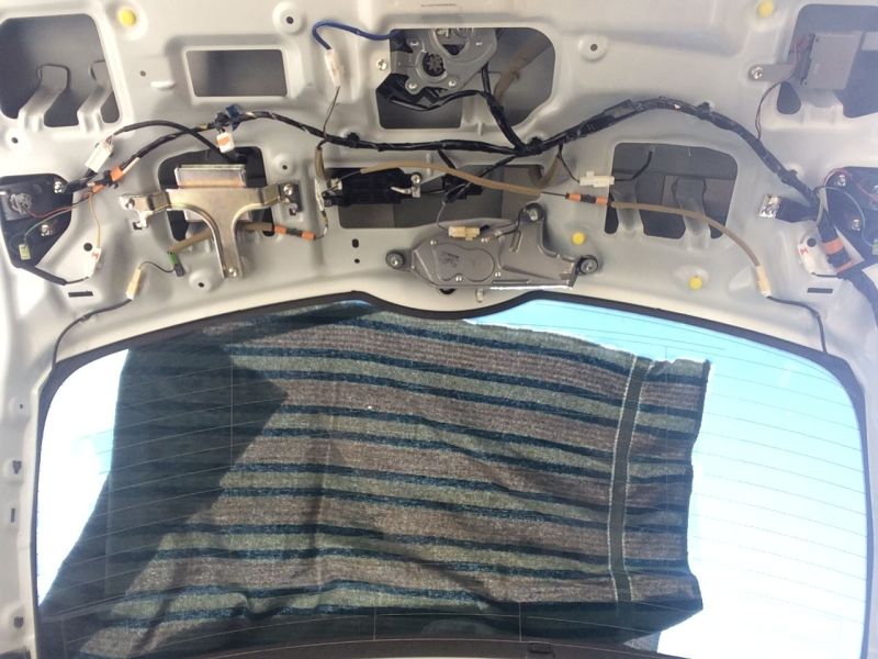 Interior of a vehicle's tailgate with wiring, mechanisms, and a cloth covering the rear window.