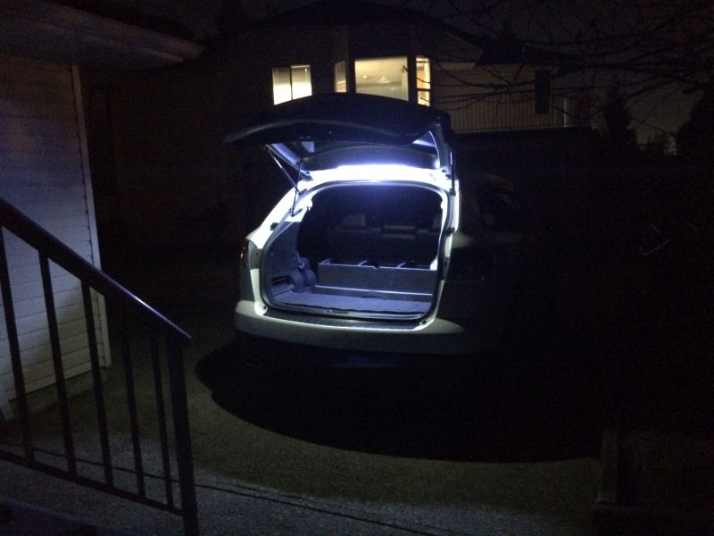 White SUV with open trunk and interior lights on at night.