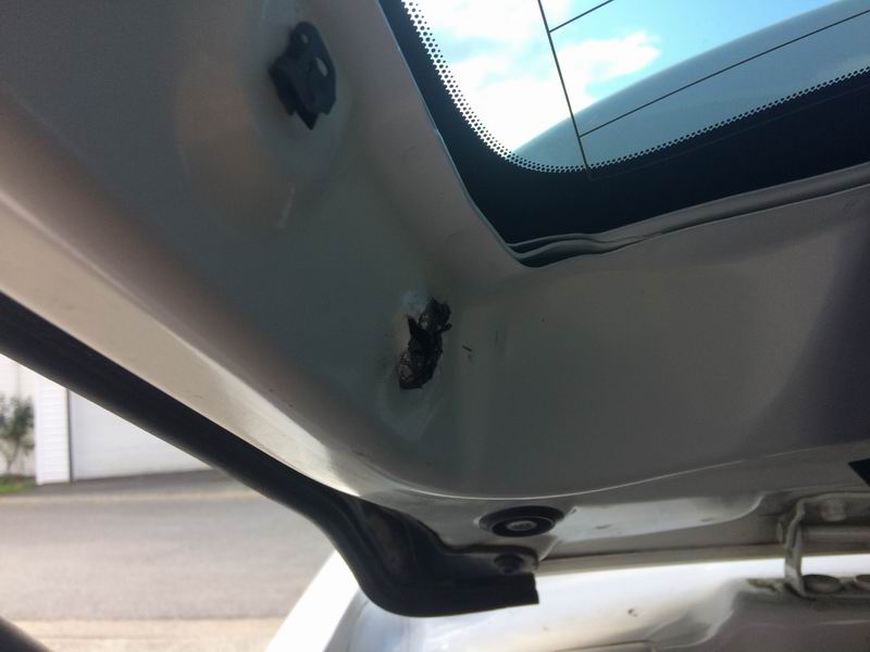 Interior of a car's rear hatch showing damage and a rubber seal.