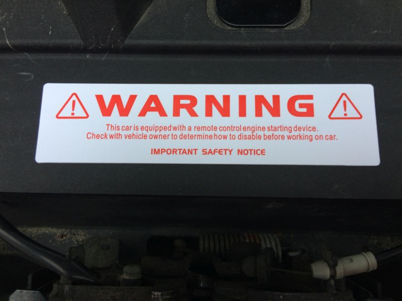 Warning sticker under vehicle hood about remote engine start device.