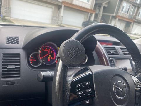 2009 Mazda CX-9 - Interior view of a 2009 Mazda CX-9 showing the steering wheel, dashboard, and instrument cluster. A steering wheel spinner knob is attached…